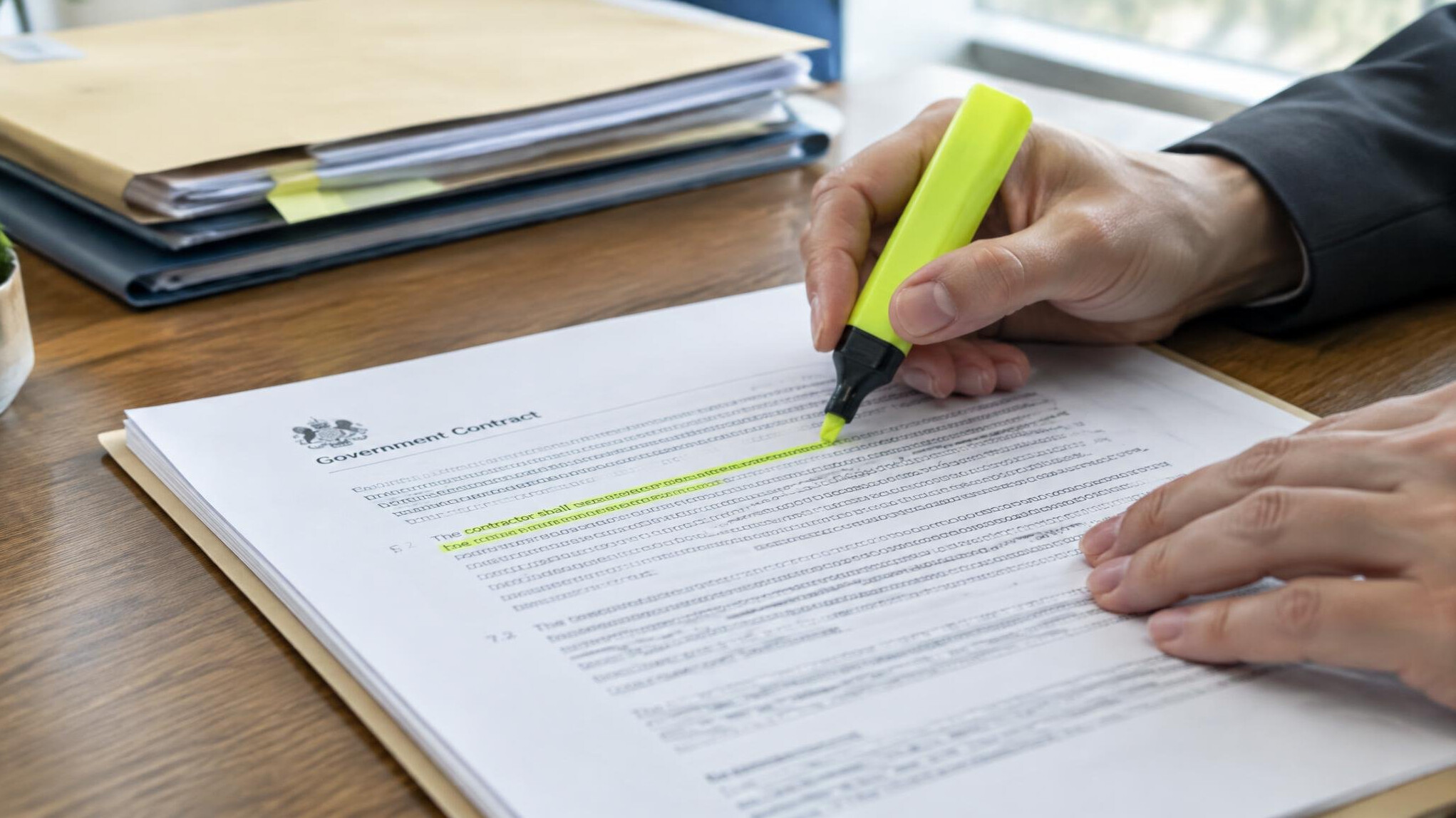 Close-up of hands marking a printed government contract document with a highlighter